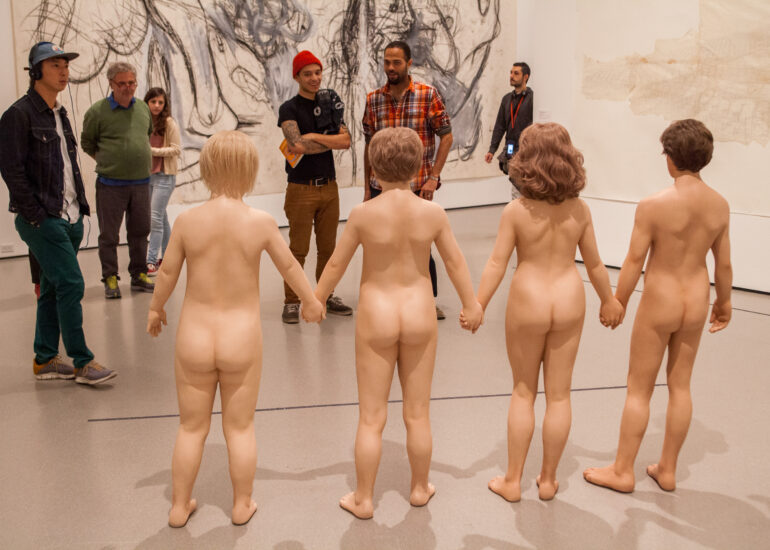 Pascal Meyer - Un groupe de touristes fait face, dans un musée, à quatre statues réalistes représentant des personnes nues